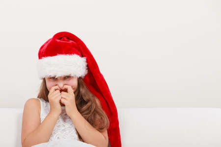 Cute little girl kid in red santa claus hat and white dress giggling. Chrtistmas holiday season.の写真素材