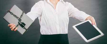Businesswoman holding document and tablet. Choice between digital and physical data storage. Woman with padlock chained file and pc computer.の写真素材
