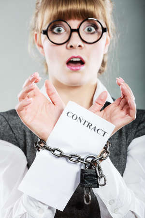 Business concept. Serious businesswoman with chained hands holding contractの写真素材