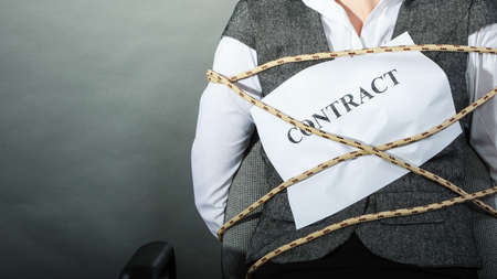 Closeup of businesswoman bound by contract terms and conditions. Woman tied becoming slave. Business and law concept.の写真素材