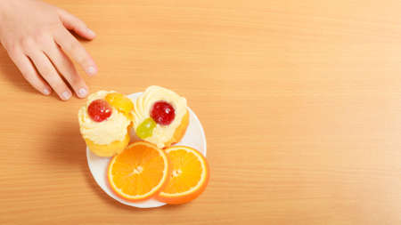 Human hand taking delicious cake with sweet cream and fruits on top. Appetite and gluttony concept.の写真素材