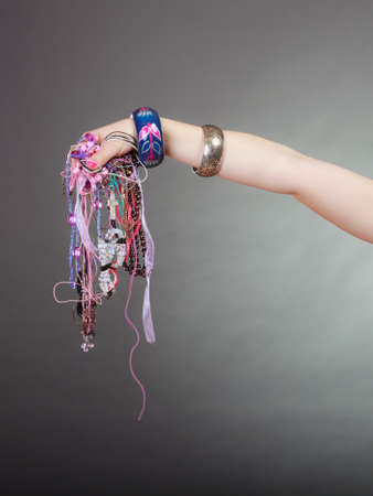 Closeup of woman hand palm holding many plentiful of precious jewelry necklaces beads. Fashion girl in studio on gray.の写真素材