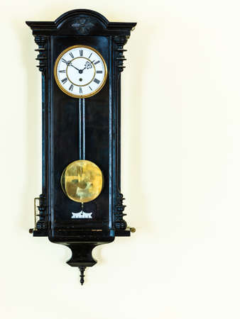 old big wooden pendulum clock hanging on wall