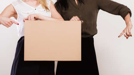 Advertisement concept. Two women caucasian and african with blank board empty banner pointing with finger studio shotの写真素材