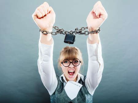 Business and stress concept. Furious businesswoman in glasses with chained hands holding contract grunge backgroundの写真素材
