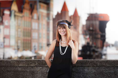 Flapper girl. Retro style fashion vintage woman from roaring 1920s outdoor on the street. Old town Gdansk Danzig in the backgroundの写真素材