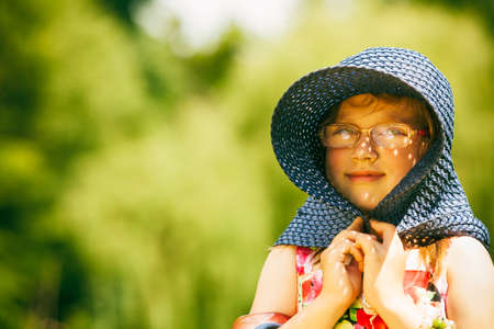 Little girl child wearing big hat on picnic. Summer vacation leisure. Happy kid relaxing in park meadow.の写真素材