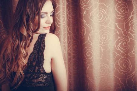 Portrait of sexy gorgeous woman by curtain. Attractive sensual young girl with long hair in...