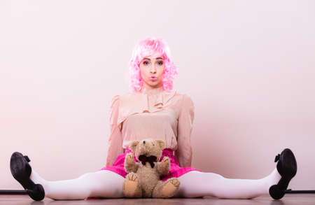 Mental disorder concept. Young childlike woman wearing like puppet doll holding teddy bear toy studio shotの写真素材