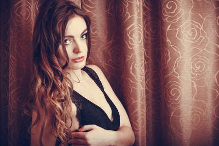 Portrait of sexy gorgeous woman by curtain. Attractive sensual young girl with long hair in lingerie. Female fashion.の写真素材