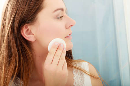 Woman removing makeup with cotton swab pad from face. Young girl taking care of skin. Skincare concept.の写真素材