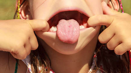 Closeup of funny kid little girl making silly face sticking out tongue. Face expression.
