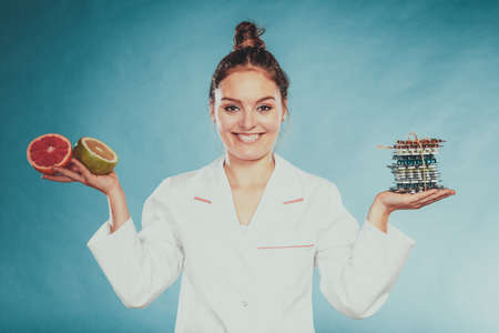 Dietitian nutritionist woman holding diet weight loss tablets pills and grapefruits. Choice between natural and synthetic way of slimming dieting. Health care.の写真素材