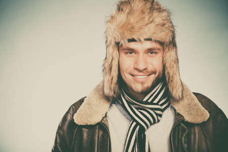 portrait of happy man with half shaved face beard hair in fur hat and scarf. smiling handsome guy on...