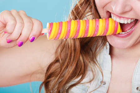 summer holidays happiness concept. happy joyful and cheerful young woman female model eating  ice pop on blue backgroundの写真素材