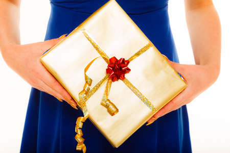 People celebrating holidays, love and happiness concept - girl blue dress with golden gift box isolatedの写真素材