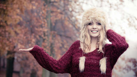 Portrait of pretty smiling woman in fall forest park with open empty palm hand for copy space. Happy...