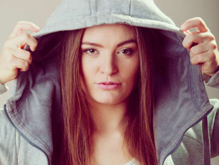 Portrait of rebellious pensive thoughtful teenager girl wearing sweatshirt with hood.の写真素材