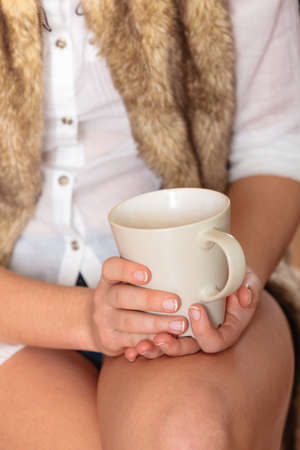 Young girl holding tea cup in hands. Woman having a break.の写真素材