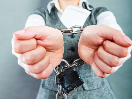Business concept. Serious businesswoman with chained hands holding contractの写真素材