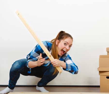 Woman assembling wooden furniture using screwdriver. DIY enthusiast. Young girl doing home improvement.の写真素材