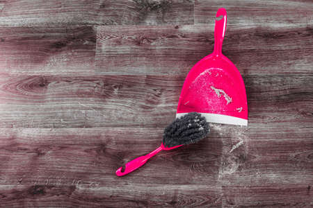 Cleaning and home concept. Sweeping brush small whisk broom and dustpan for house work with garbage on floor indoors.の写真素材