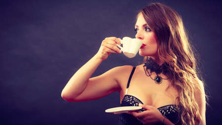 Sexuality and sensuality of women. Sexy gorgeous alluring woman model in lingerie underwear holding cup of tea coffee beverage. Indoor.の写真素材