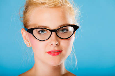 Optometrist, oculist and ophthalmologist concept. Young blonde woman with eyeglasses on blue...