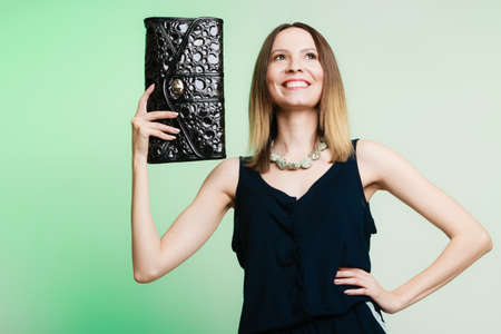 Elegant outfit. Young stylish woman fashionable girl holding black handbag on green. Fashion and female beauty. Studio shot.の写真素材