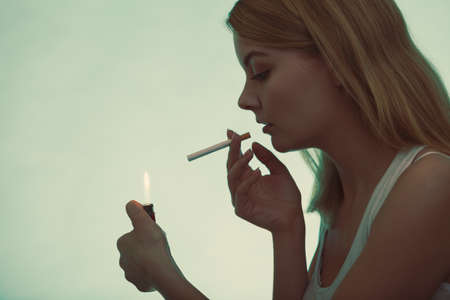 Pretty girl smoking cigarette using lighter. Addicted nicotine problems in young age. Addiction...