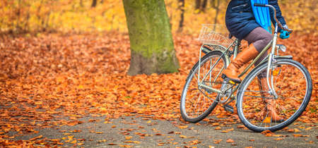 Active woman girl riding bike bicycle relaxing in fall autumn park. Healthy lifestyle and recreation leisure activity.の写真素材