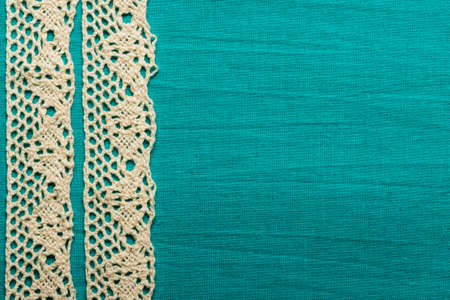 Retro border for invitations celebration. Vintage white lace over green blue textile background.