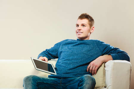 Modern technology leisure and relaxation concept. Young man with pc computer digital tablet on couch