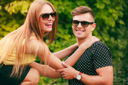 Love and happiness. Young happy couple lovers wearing sunglasses dating in summer park outdoor.の写真素材