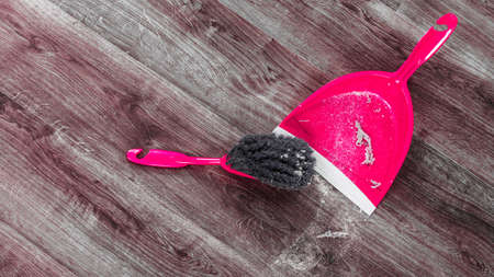 Cleaning and home concept. Sweeping brush small whisk broom and dustpan for house work with garbage on floor indoors.の写真素材