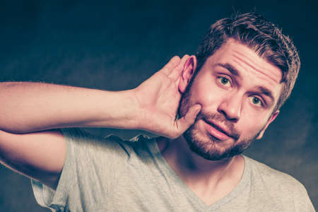 Gossip man eavesdropping with hand to ear. Guy overhearing listening to rumors. Spying and secret concept.  の写真素材