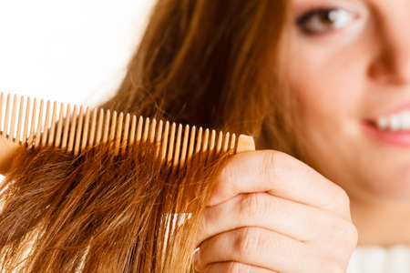Smiling woman combing with brush and pulls at her long hair. Being happy for nice look in daily activity.の写真素材