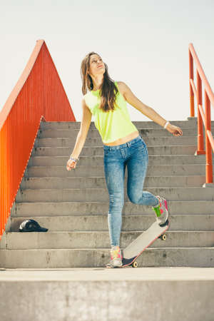 Cool skate young long haired girl riding skateboard on the urban stairs. Active lifestyle funky in...