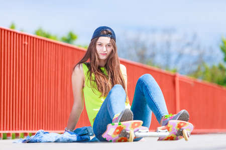 Summer sport and active lifestyle. Cool teenage girl skater riding skateboard on the street. Outdoor.の写真素材