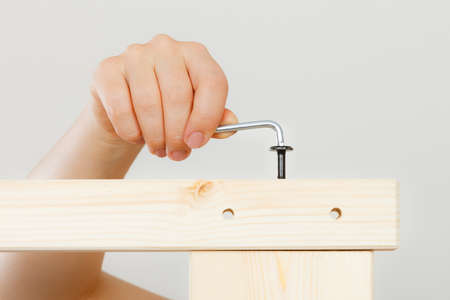 Human hand assembling wooden furniture using hex key. DIY enthusiast. Home improvement.の写真素材