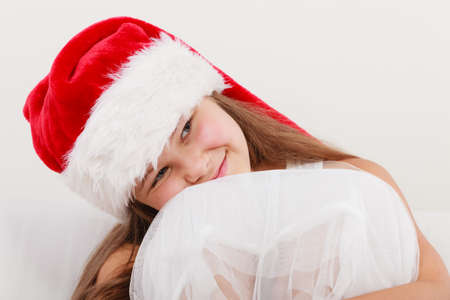 Cute little girl kid in red santa claus hat and white dress. Chrtistmas holiday season.の写真素材