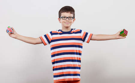 Portrait of smart cute kid little boy in glasses with magic rubik cube and platonic solid geometric figure. Education.のeditorial素材