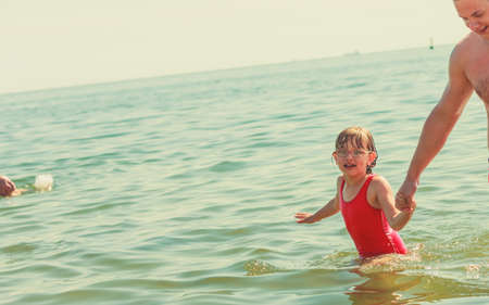 Little girl child and father having fun in ocean. Kid and man bathing in sea water. Summer vacation holiday relax.の写真素材