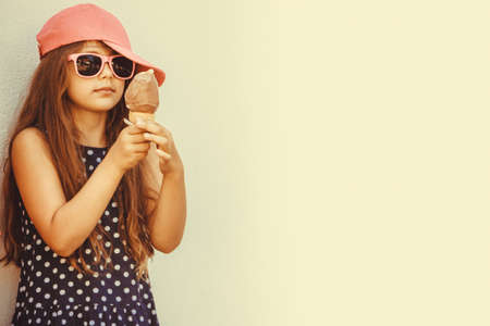 Kid eating gelato soft serve ice cream. Little girl in sunglasses enjoying summer holidays vacation. の写真素材