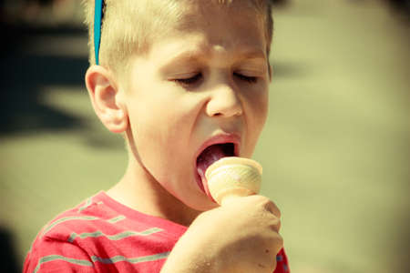 Young kid eating gelato ice cream. Boy child enjoying summer holidays vacation.の写真素材