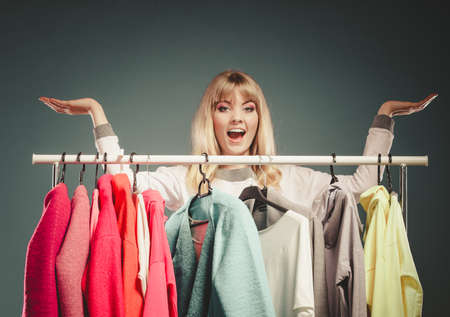 Happy smiling pretty woman with open palms hands for copy space in wardrobe. Gorgeous young girl customer shopping in mall shop. Fashion clothing sale concept.の写真素材