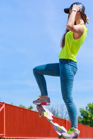 Summer sport and active lifestyle. Cool teenage girl in full length skater riding skateboard on the street. Outdoor.の写真素材