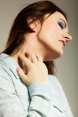 Health problem. Young woman scratching her itchy nack with allergy rashの写真素材