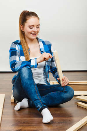 Woman assembling wooden furniture using screwdriver. DIY enthusiast. Young girl doing home improvement.の写真素材