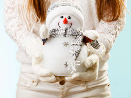 Young woman holding xmas snowman. Girls hands in woolen white gloves. Christmas time concept.の写真素材